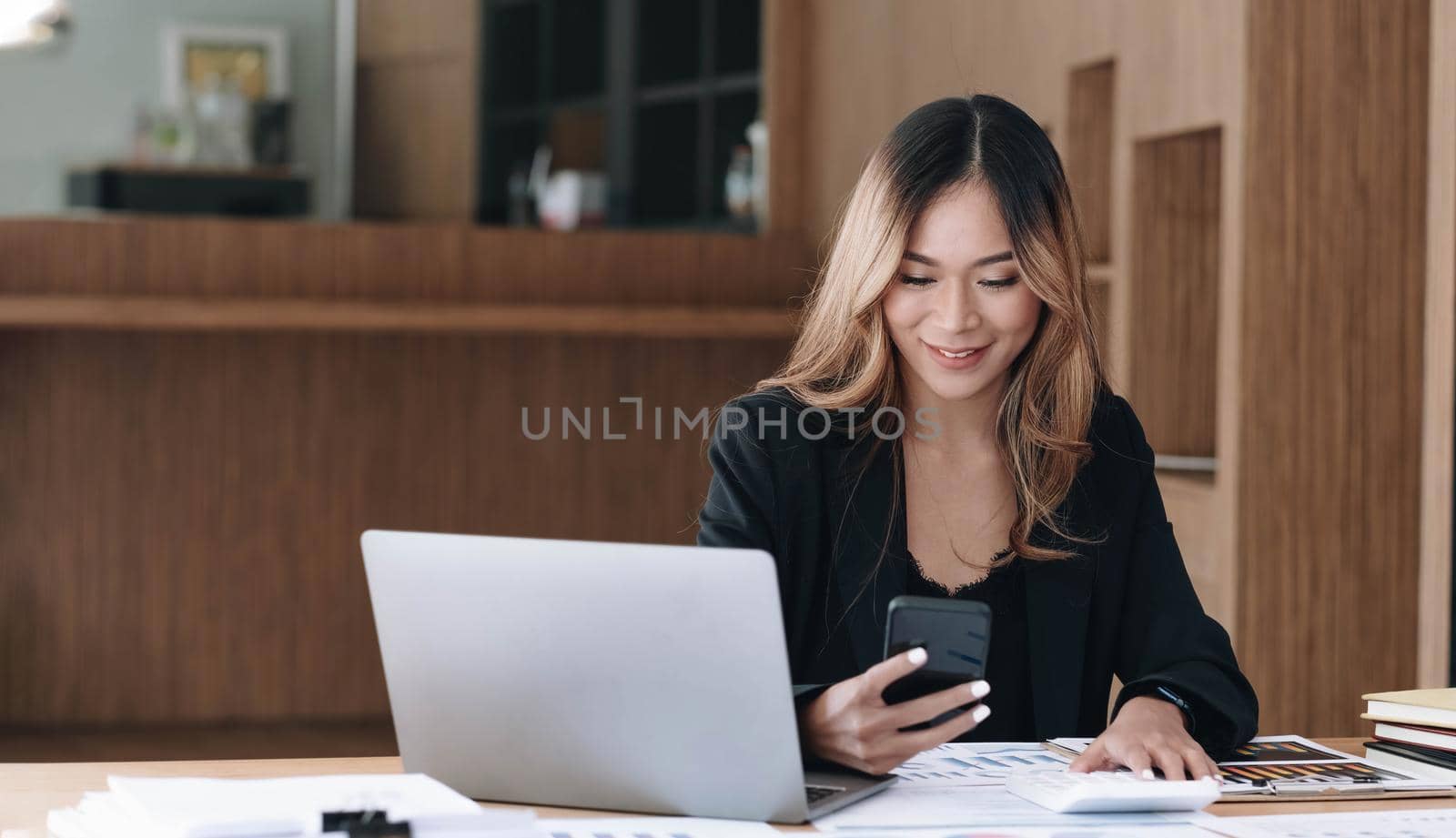 Asian businesswoman relax and enjoy playing mobile phone at office. by wichayada