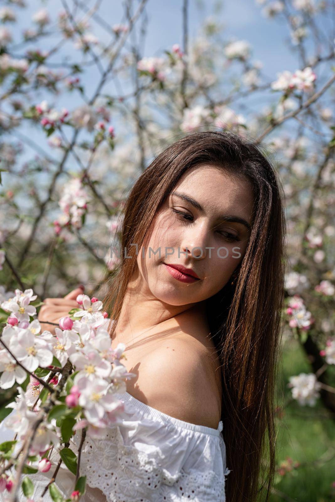 Spring concept. Nature.Young caucasian woman enjoying the flowering of an apple trees, walking in spring apple gardens