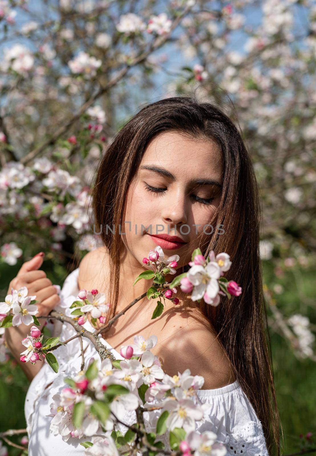 Spring concept. Nature.Young caucasian woman enjoying the flowering of an apple trees, walking in spring apple gardens