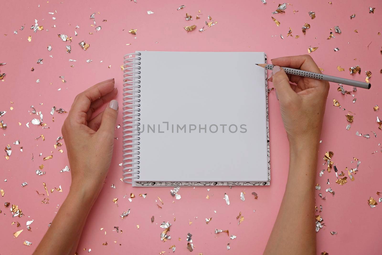 Blank notebook and female hands with pencil on festive pink background by natus111