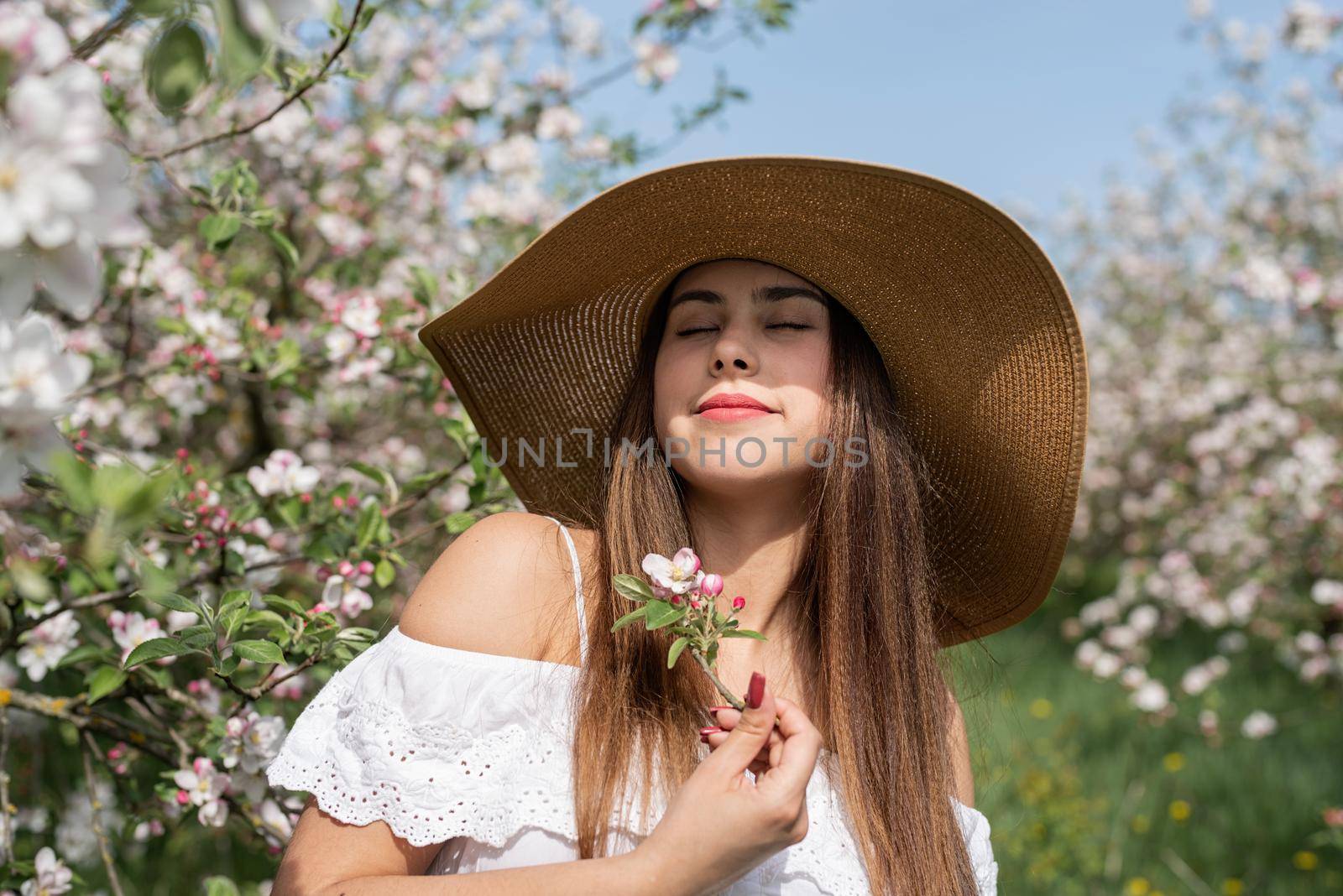 Young caucasian woman enjoying the flowering of an apple trees by Desperada