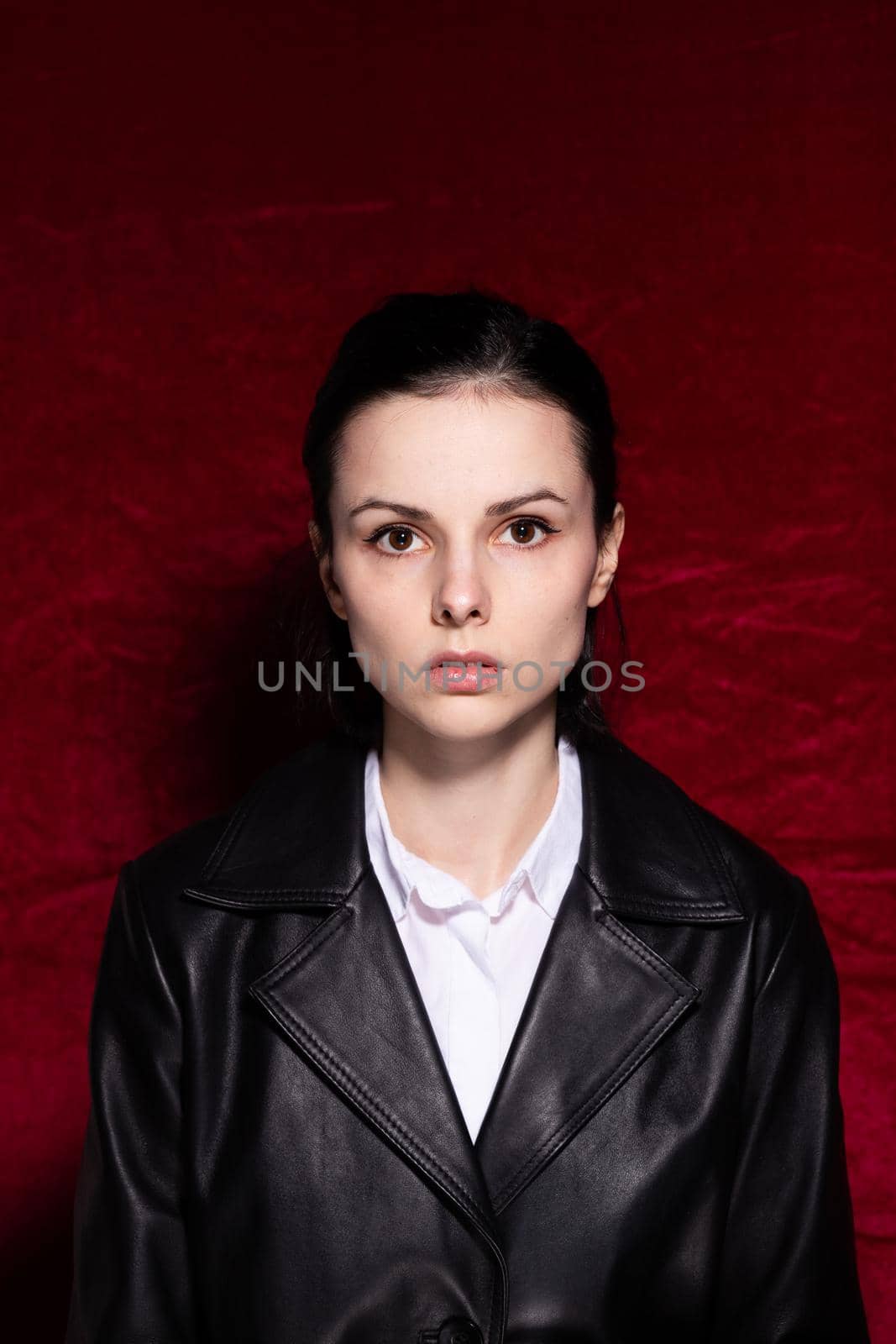 Woman in white shirt and black leather jacket on red velvet background. High quality photo