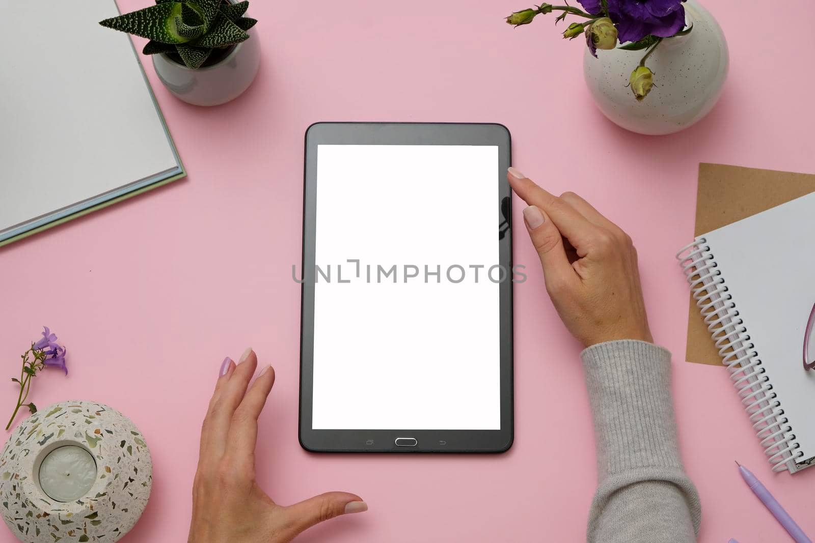 Mockup image of hands holding tablet PC on pink office desk. Flat lay.