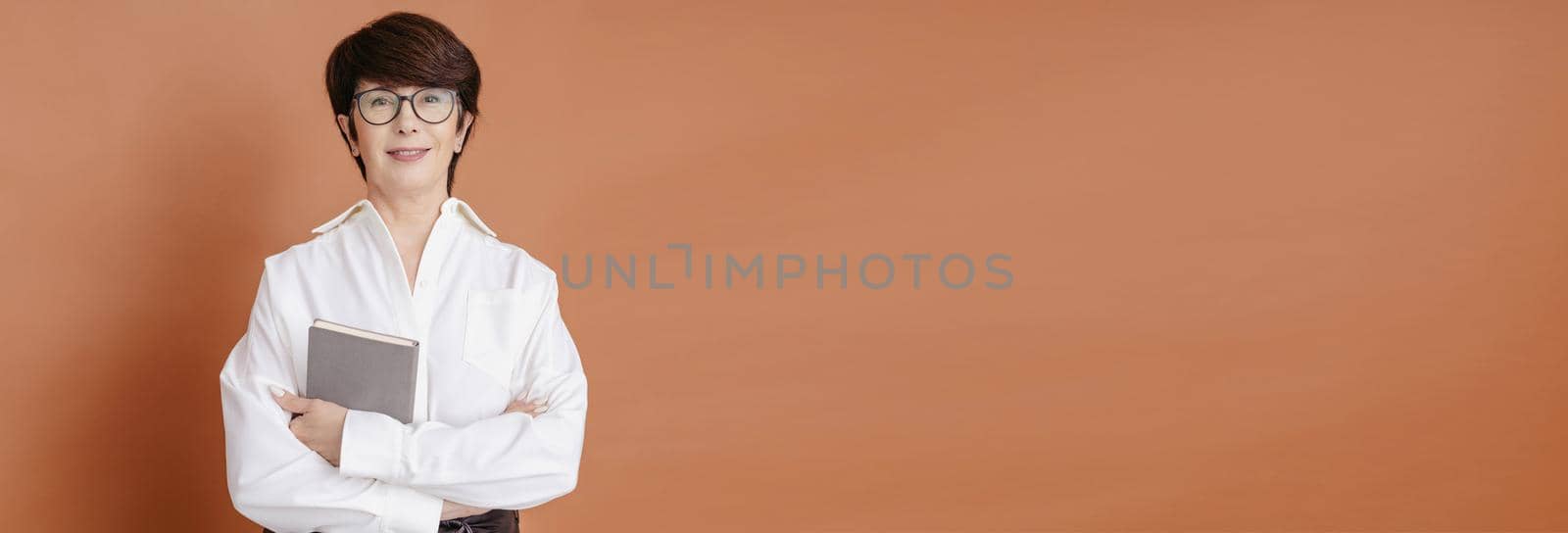 Mature confident business woman on brown background - banner and blank space for advertising. High quality photo