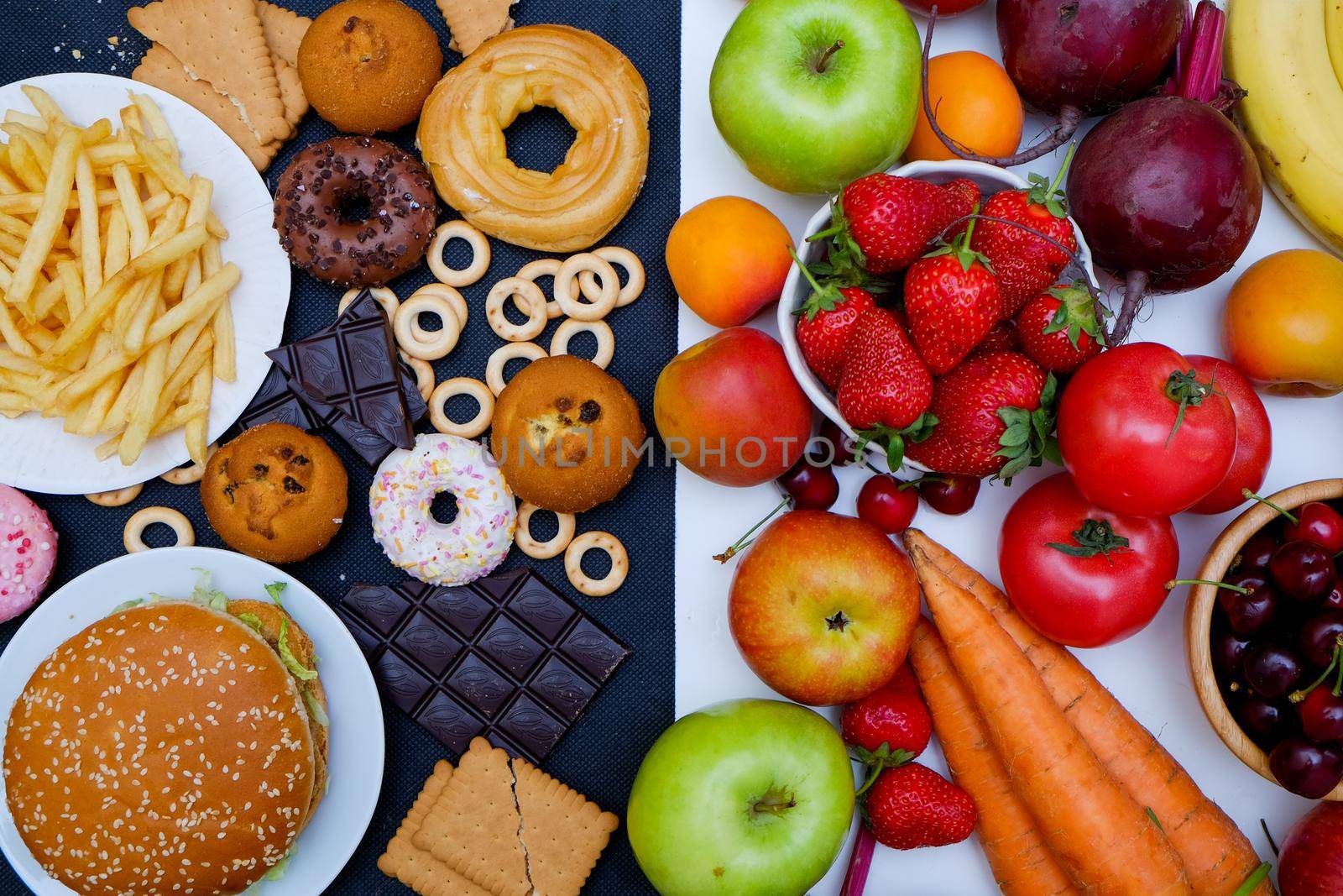 Concept photo of healthy and unhealthy food. Fruits and vegetables vs donuts,sweets and burgers by natus111