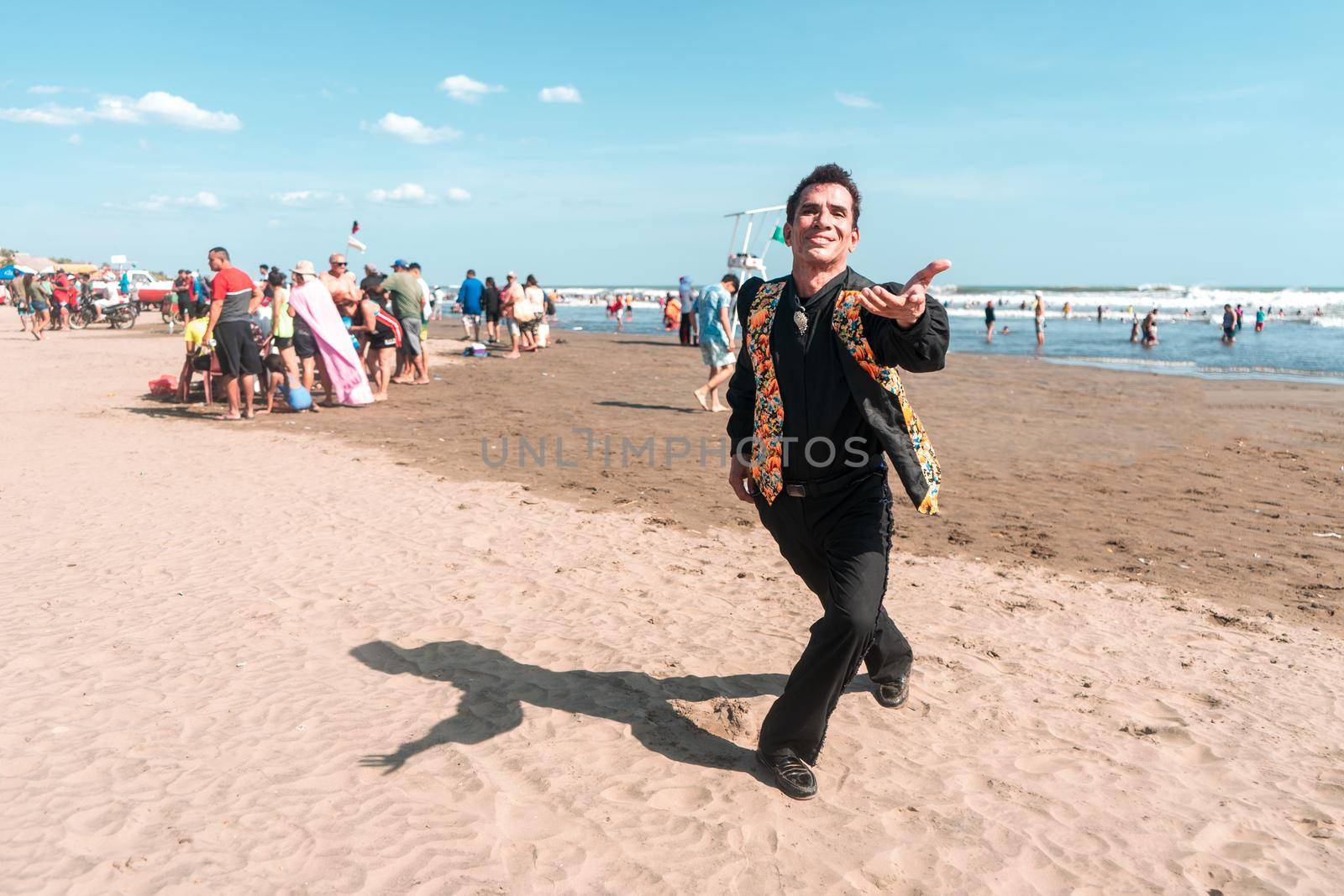 Portrait of a Latin man dressed in black and with a flowered vest dancing, blowing a kiss at the camera. Party concept in the summer break of Latin America. by cfalvarez