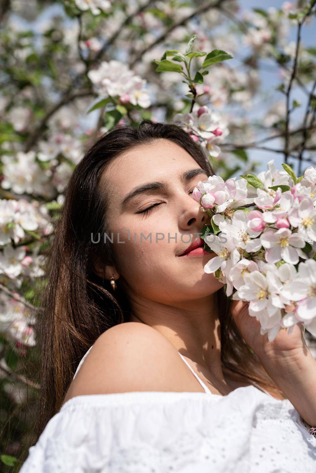 Spring concept. Nature.Young caucasian woman enjoying the flowering of an apple trees, walking in spring apple gardens