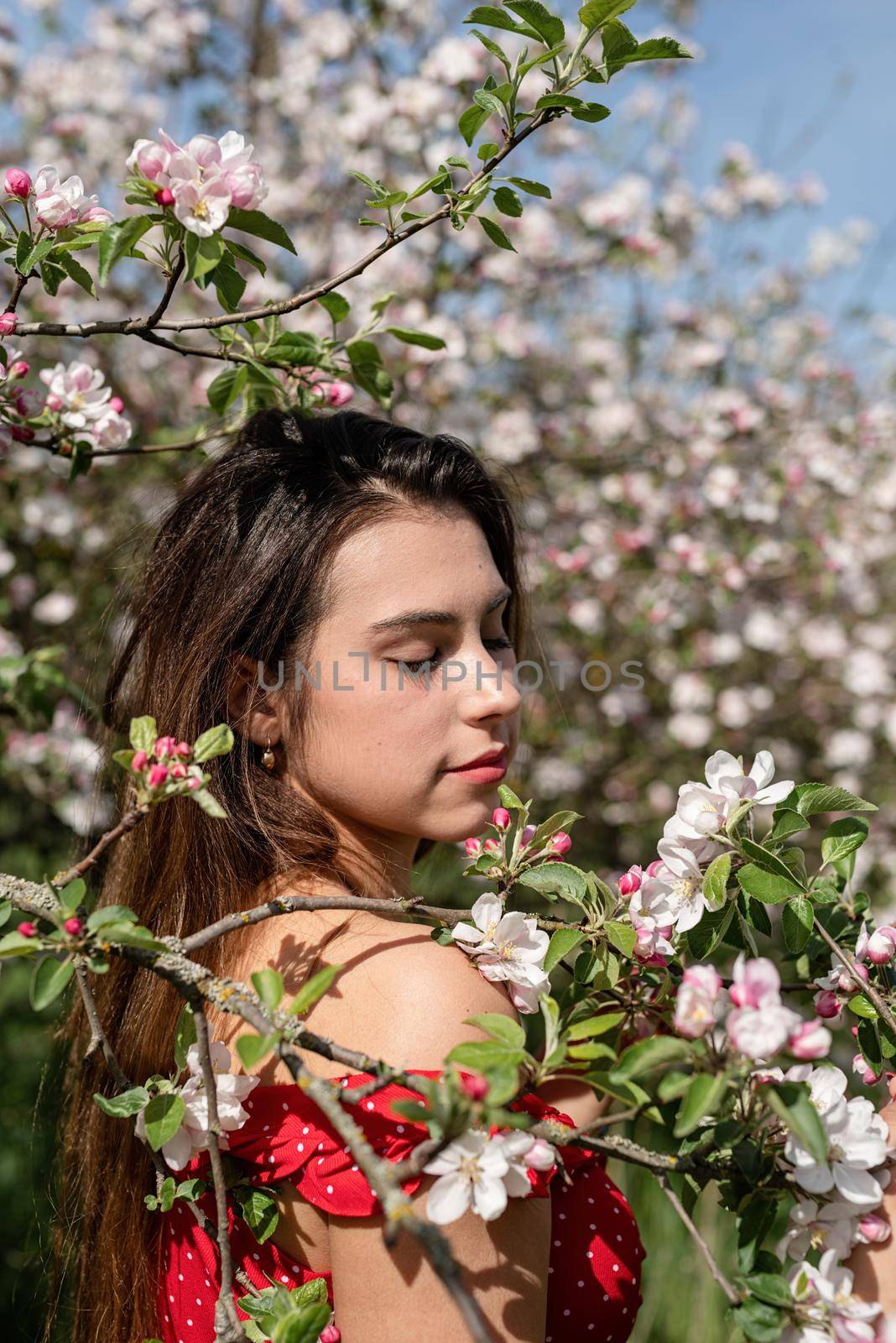 Young caucasian woman enjoying the flowering of an apple trees by Desperada