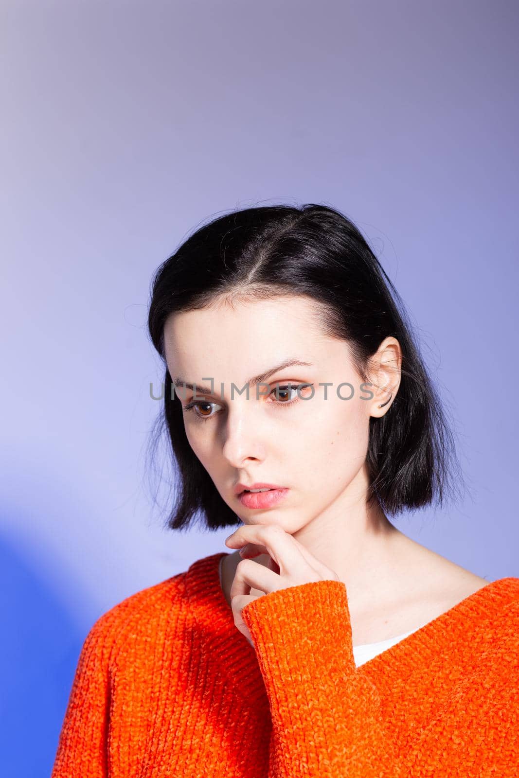beautiful girl in an orange sweater on a blue background. High quality photo
