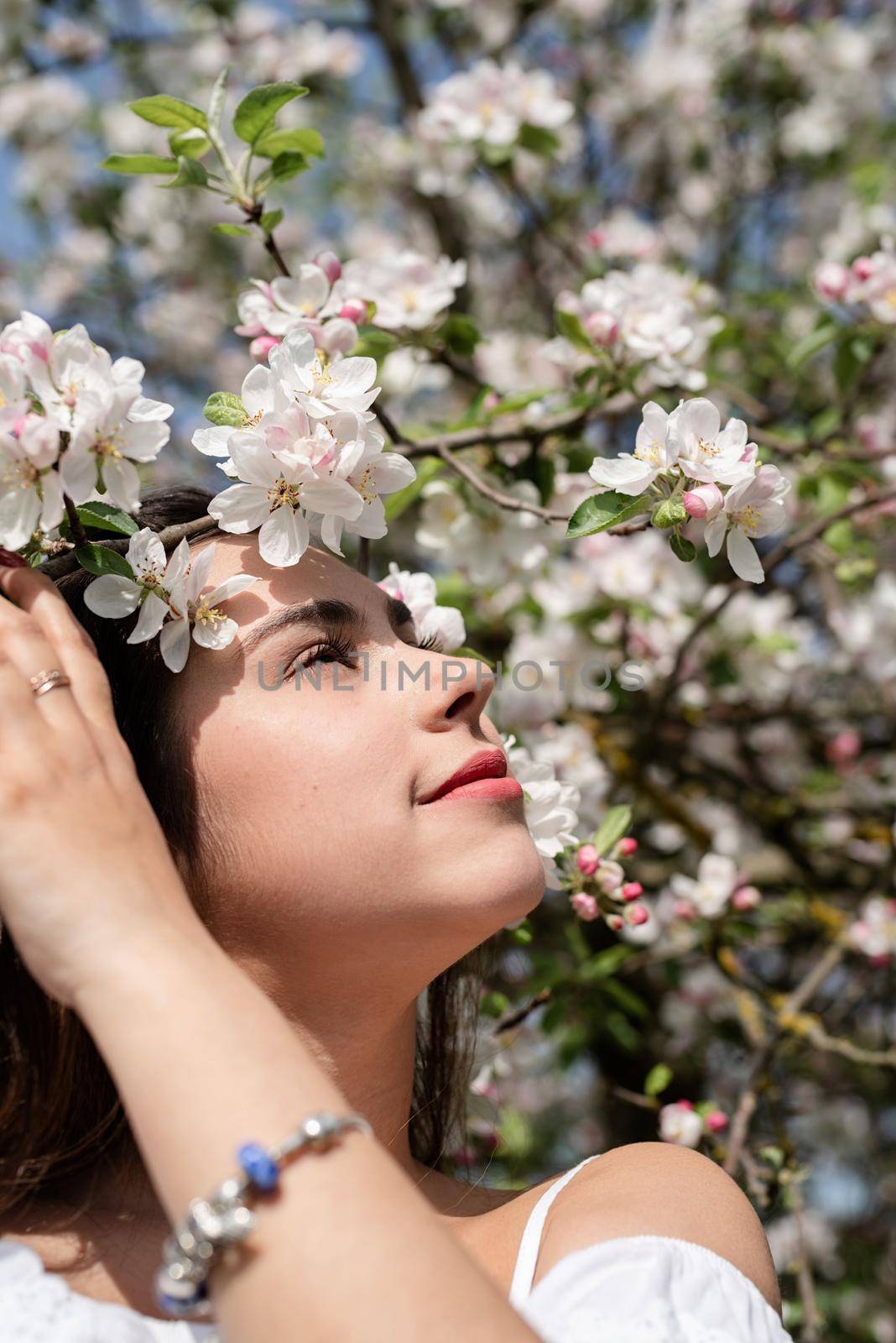 Spring concept. Nature.Young caucasian woman enjoying the flowering of an apple trees, walking in spring apple gardens