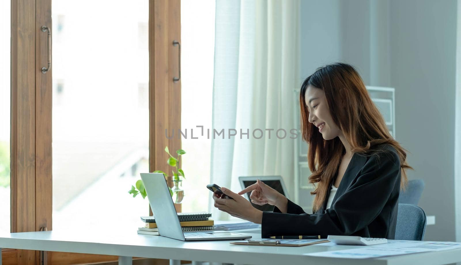 Asian businesswoman relax and enjoy playing mobile phone at office. by wichayada