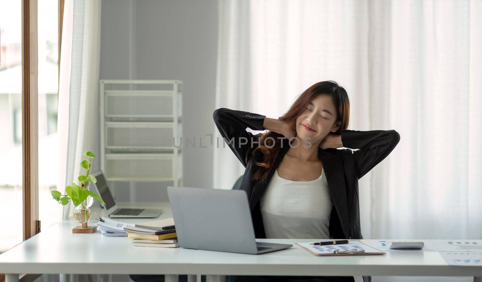 Asian woman enjoy and happy of relaxing at the office. Hold hands behind head concept of success future. by wichayada