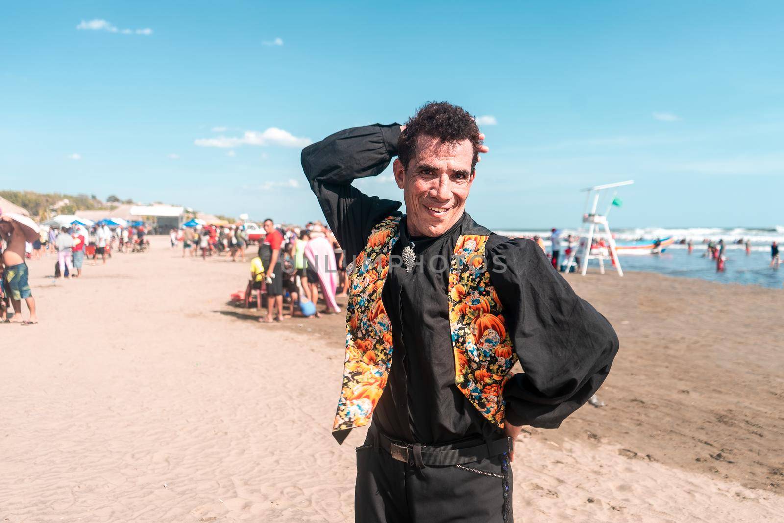 Portrait of a Latin man dressed in black and with a flowered vest dancing with one arm on his head and the other on his waist, smiling and looking at the camera. Party concept in the summer break in the caribbean by cfalvarez