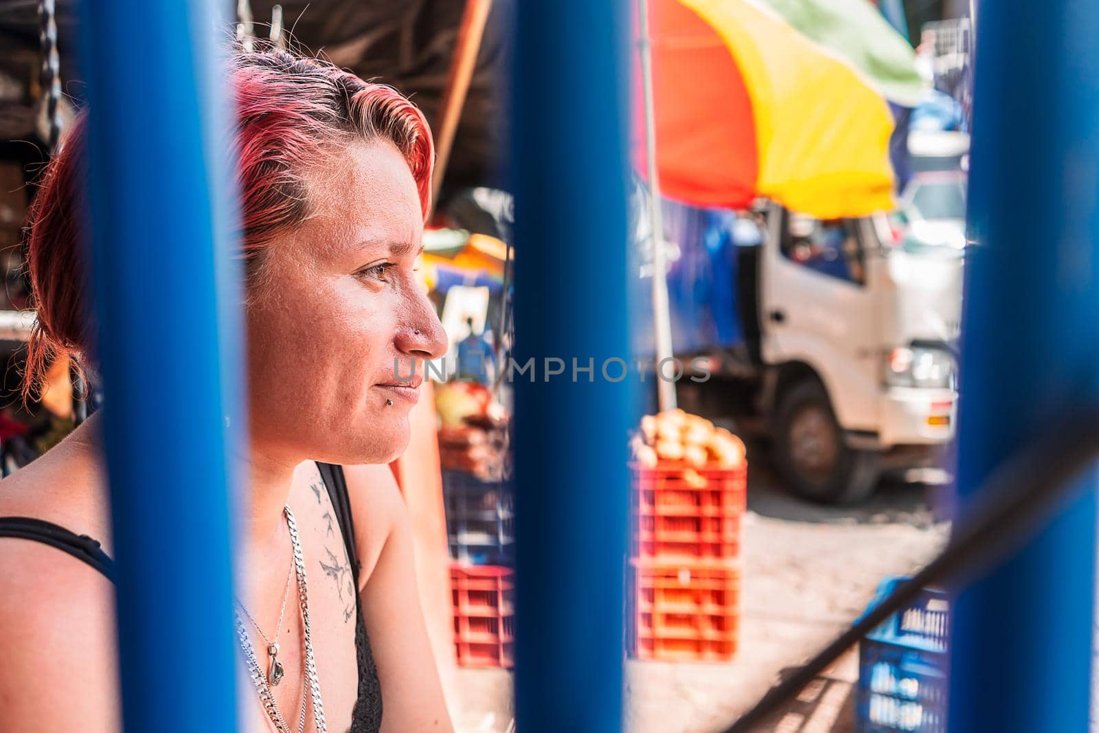 Portrait of a white Latin woman with a modern haircut with piercings on her lips and subtle tattoos in a popular market in Boaco, Nicaragua.