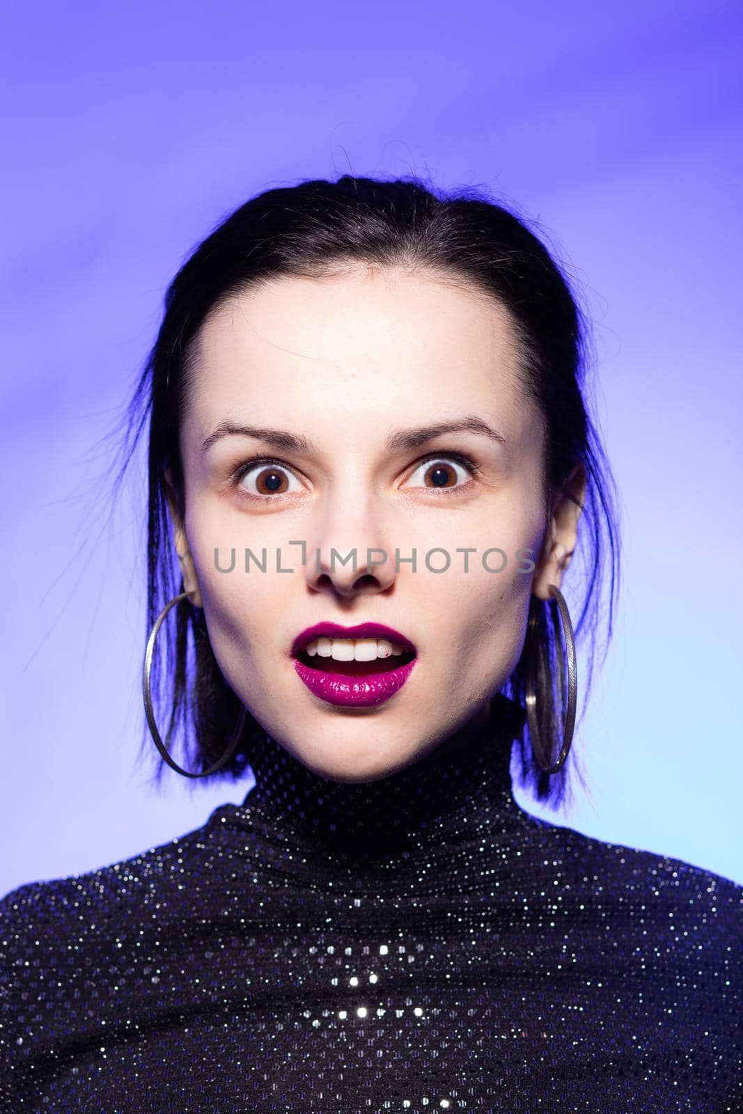 brunette woman with purple lips, blue background. High quality photo