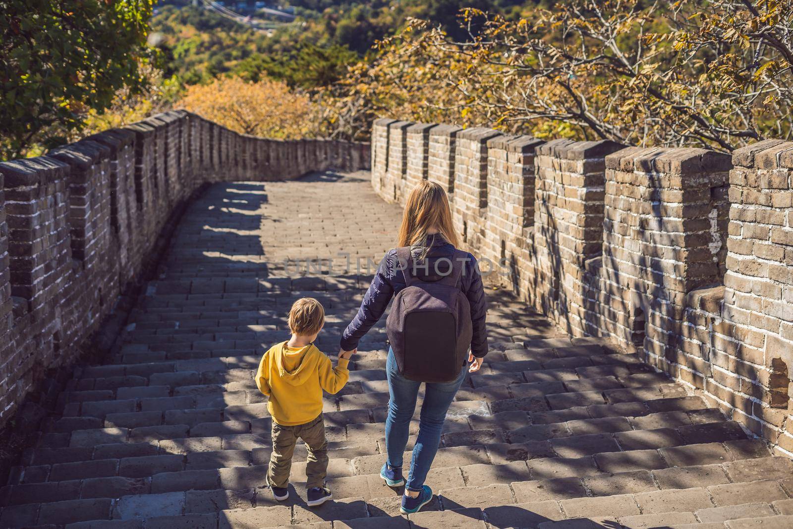 Happy cheerful joyful tourists mom and son at Great Wall of China having fun on travel smiling laughing and dancing during vacation trip in Asia. Chinese destination. Travel with children in China concept by galitskaya