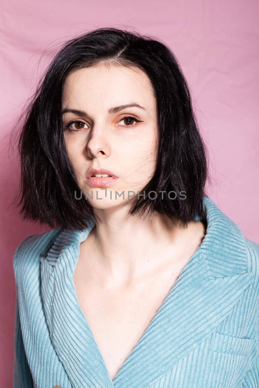portrait of a brunette woman in a blue velvet jacket on a pink background. High quality photo