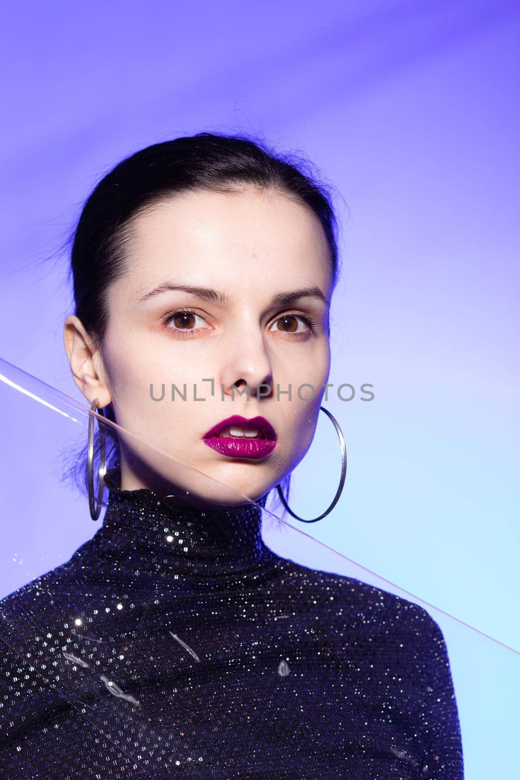 brunette woman with purple lips, blue background. High quality photo
