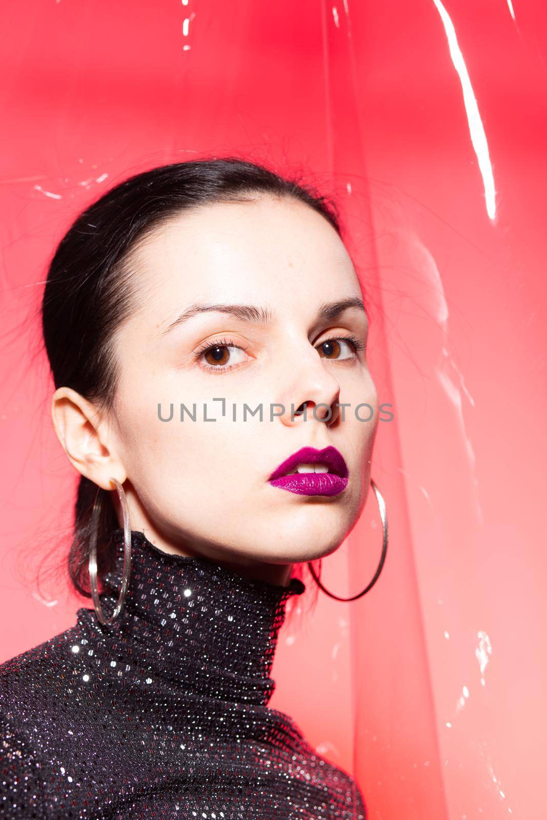 woman with purple lips in a black turtleneck with sequins on a red background by shilovskaya