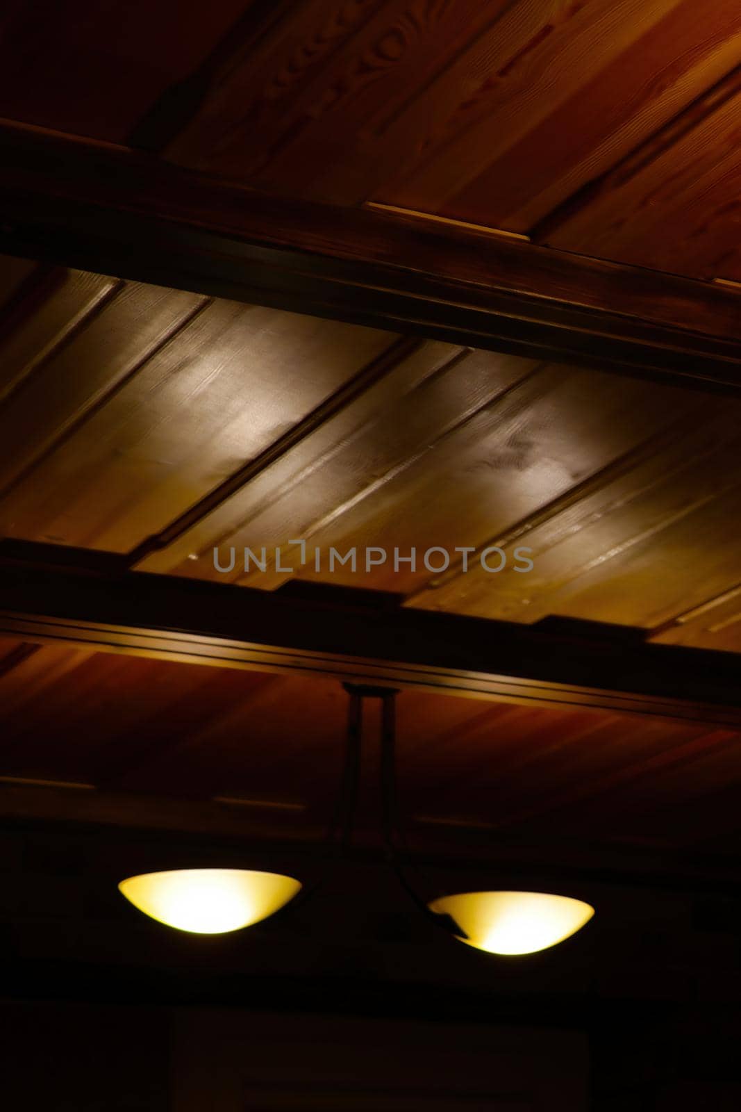 Blurry background, out of focus. Wooden ceiling with lamp, out of focus