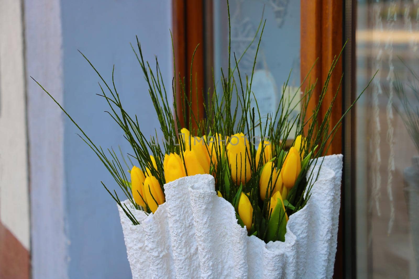 There is a bouquet of yellow tulips in a vase on the window