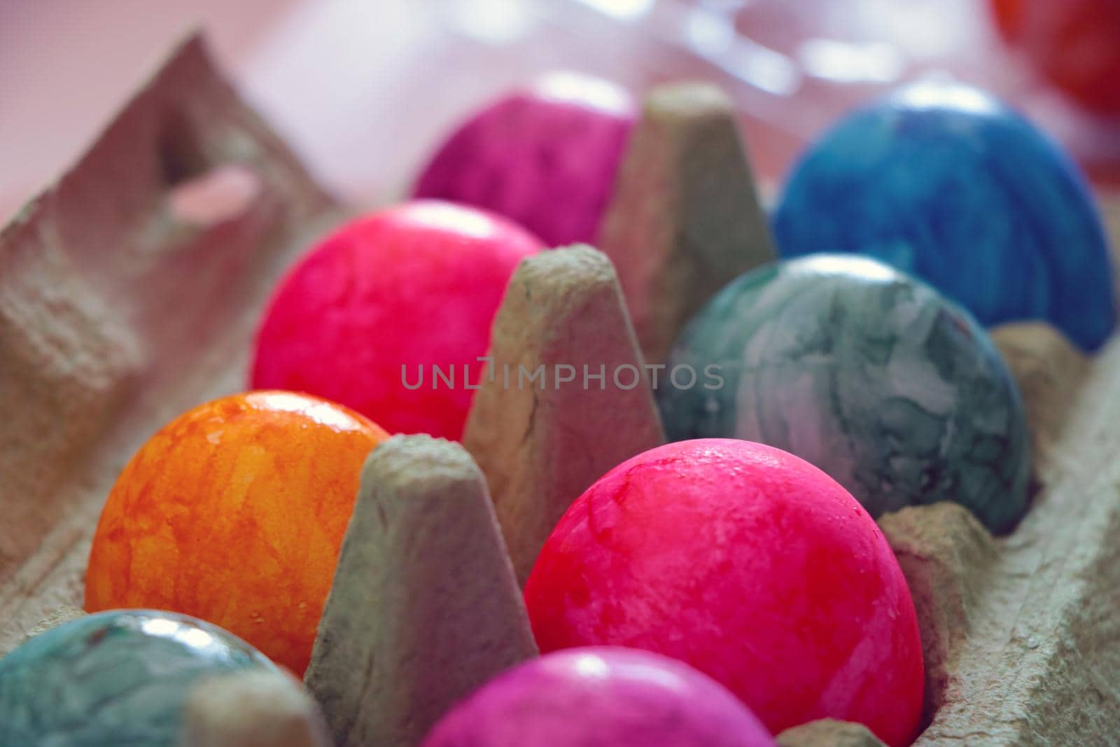 Colored multi-colored eggs in a carton box. Out of focus, blurred.