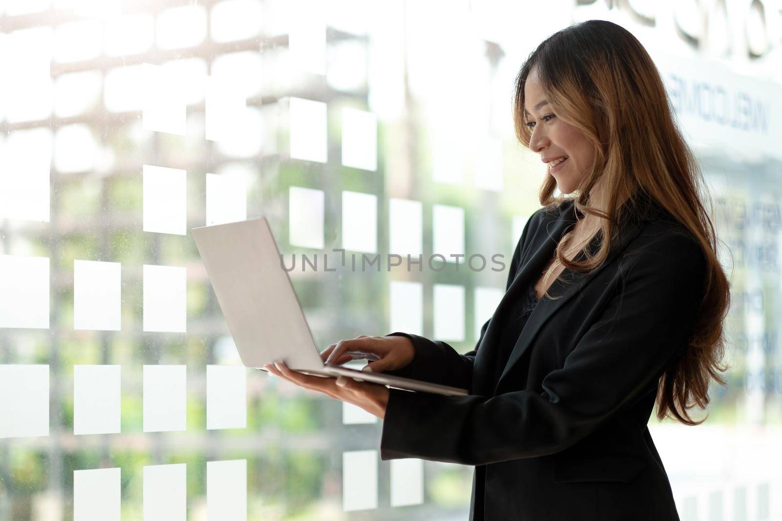 Young Asian business woman working online on a laptop in office. by wichayada