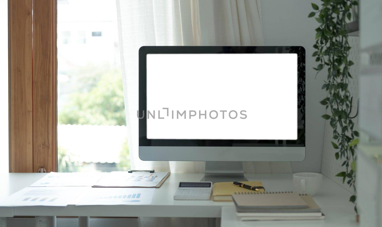 Blank screen desktop computer in minimal office room with decorations and copy space.