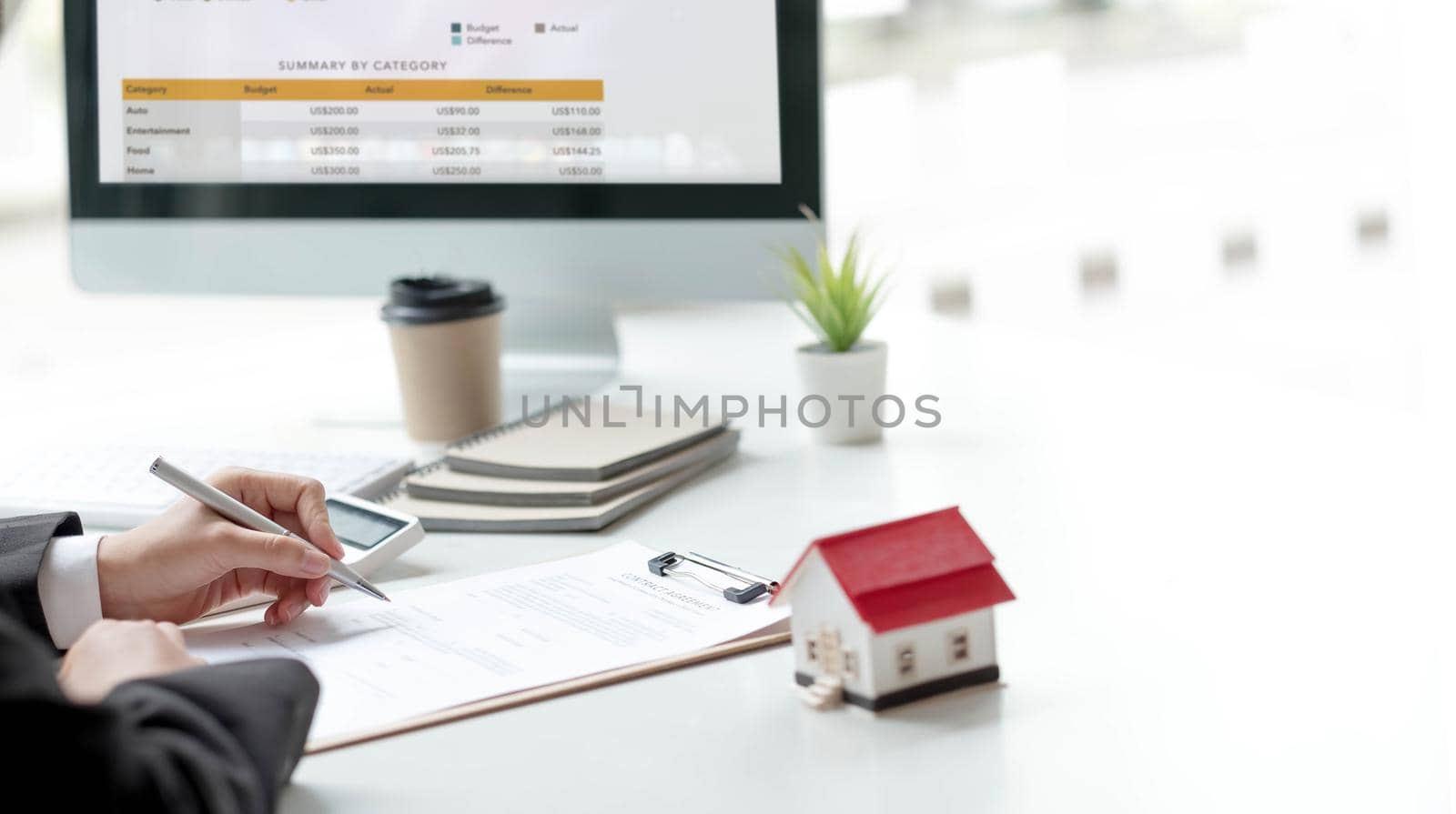 Pen handles signed documents with model houses and laptop on the table..