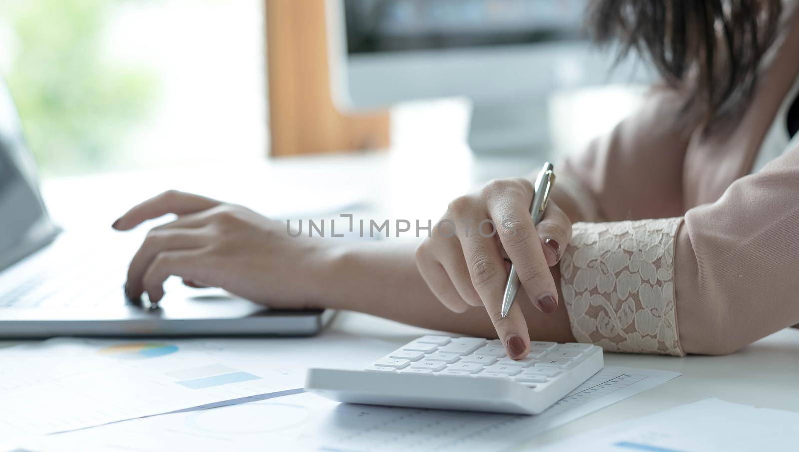 Woman accountant use calculator and computer on desk in office. Work for safe at home. finance and accounting concept.