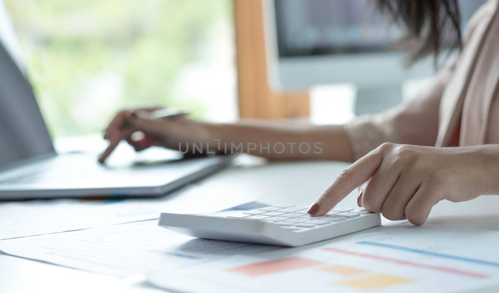 Close up young woman using calculator and laptop, checking domestic bills, sitting at table with financial documents, managing planning budget, accounting expenses, browsing internet service by wichayada