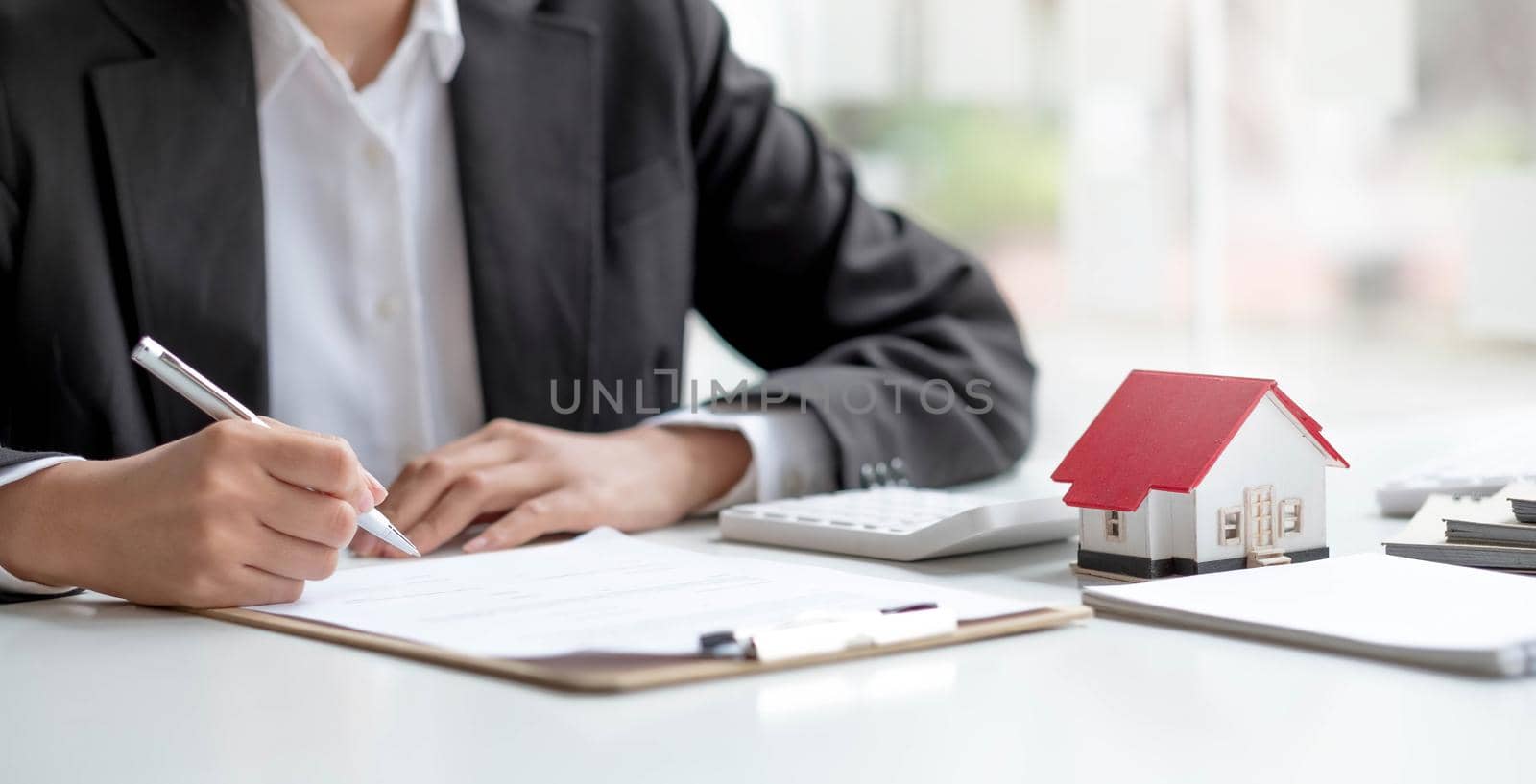 Pen handles signed documents with model houses and laptop on the table..