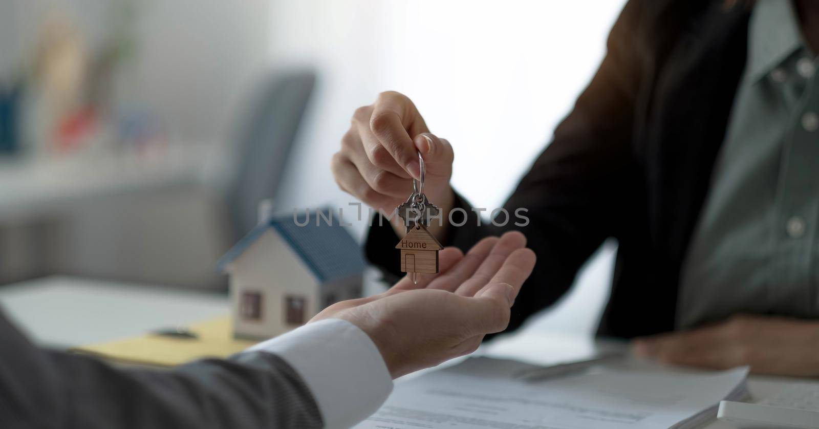 Close up hand of home,apartment agent or realtor was holding the key to the new landlord,tenant or rental.After the banker has approved and signed the purchase agreement successfully.Property concept. by wichayada