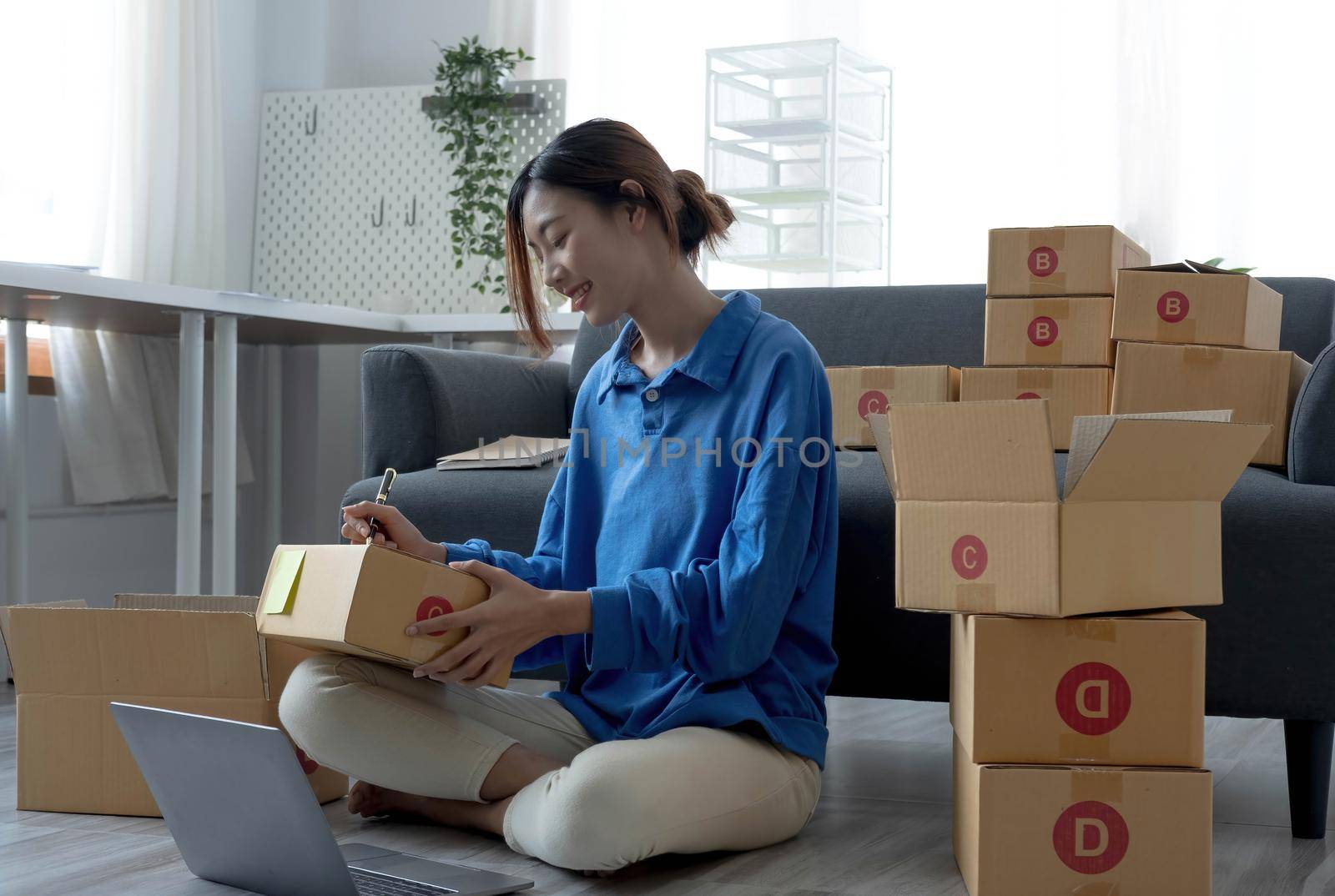 Starting small businesses SME owners female entrepreneurs Use a laptop or notebook to receive and review orders online to prepare to pack boxes, sell to customers, SME online business ideas. by wichayada