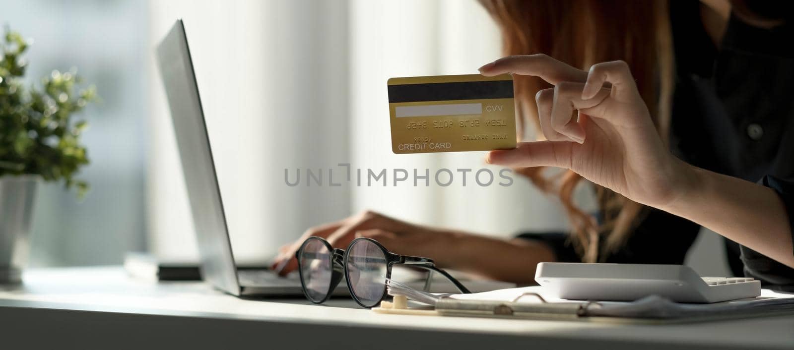 Asian woman checking online order details on computer and use the credit card information entered on the computer..