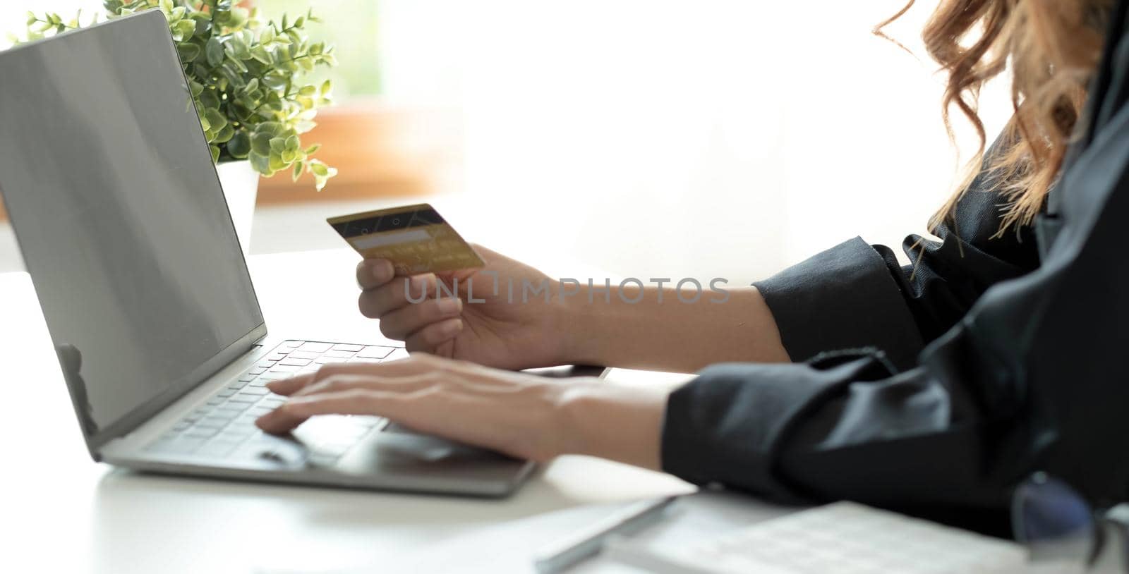 Asian woman checking online order details on computer and use the credit card information entered on the computer..