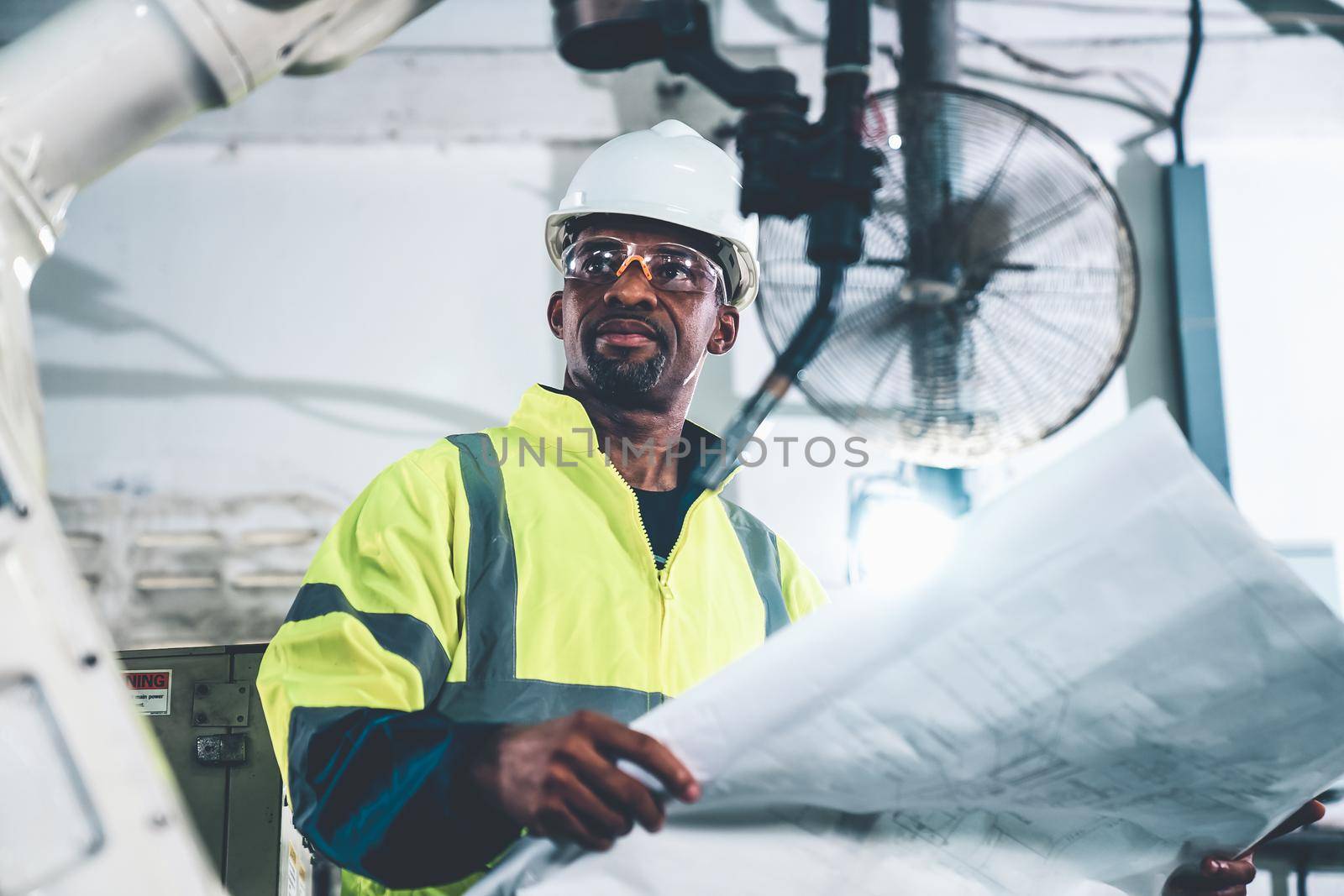 African American factory worker working with adept robotic arm in a workshop . Industry robot programming software for automated manufacturing technology .