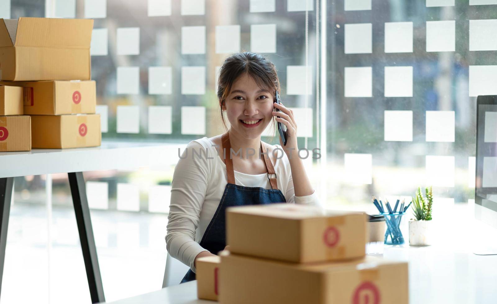 Small business entrepreneur SME freelance woman using phone call receive from customer checking product on stock at home office, online marketing packaging delivery box, SME e-commerce concept..