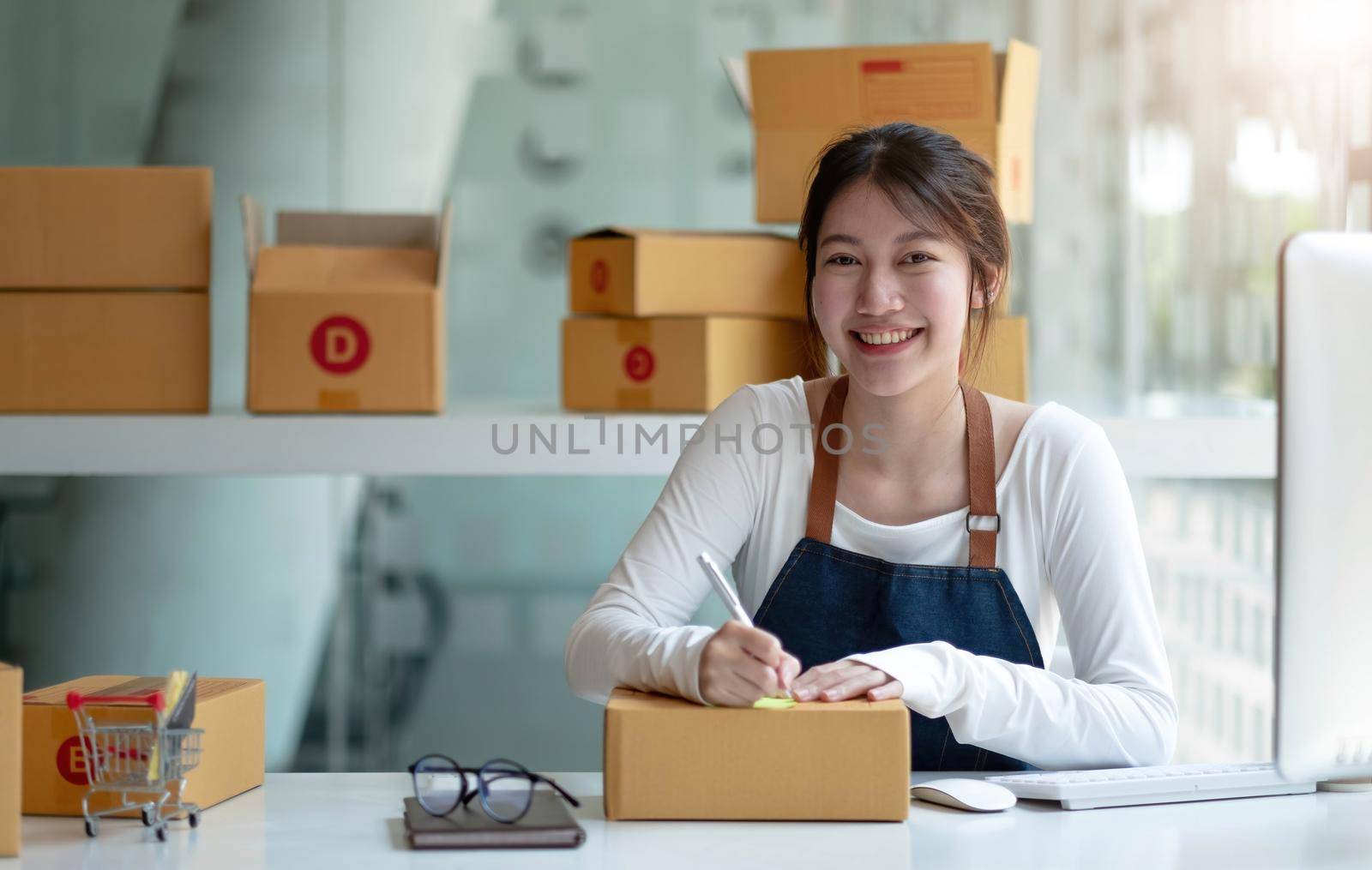 Portrait of Asian young woman working with a box at home the workplace.start-up small business owner, small business entrepreneur SME or freelance business online and delivery concept..