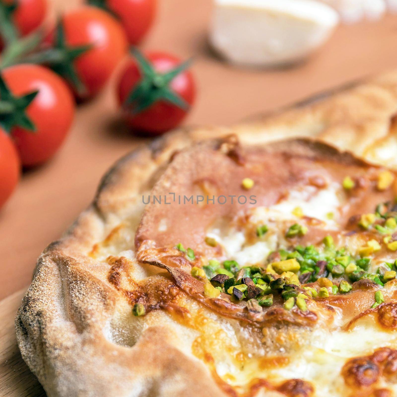 Delicious gourmet pizza with ham, and pistachios. Close-up.