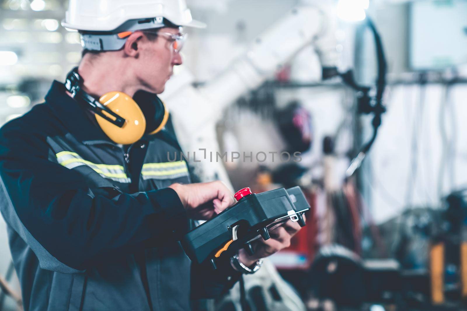 Young factory worker working with adept robotic arm in a workshop . Industry robot programming software for automated manufacturing technology .