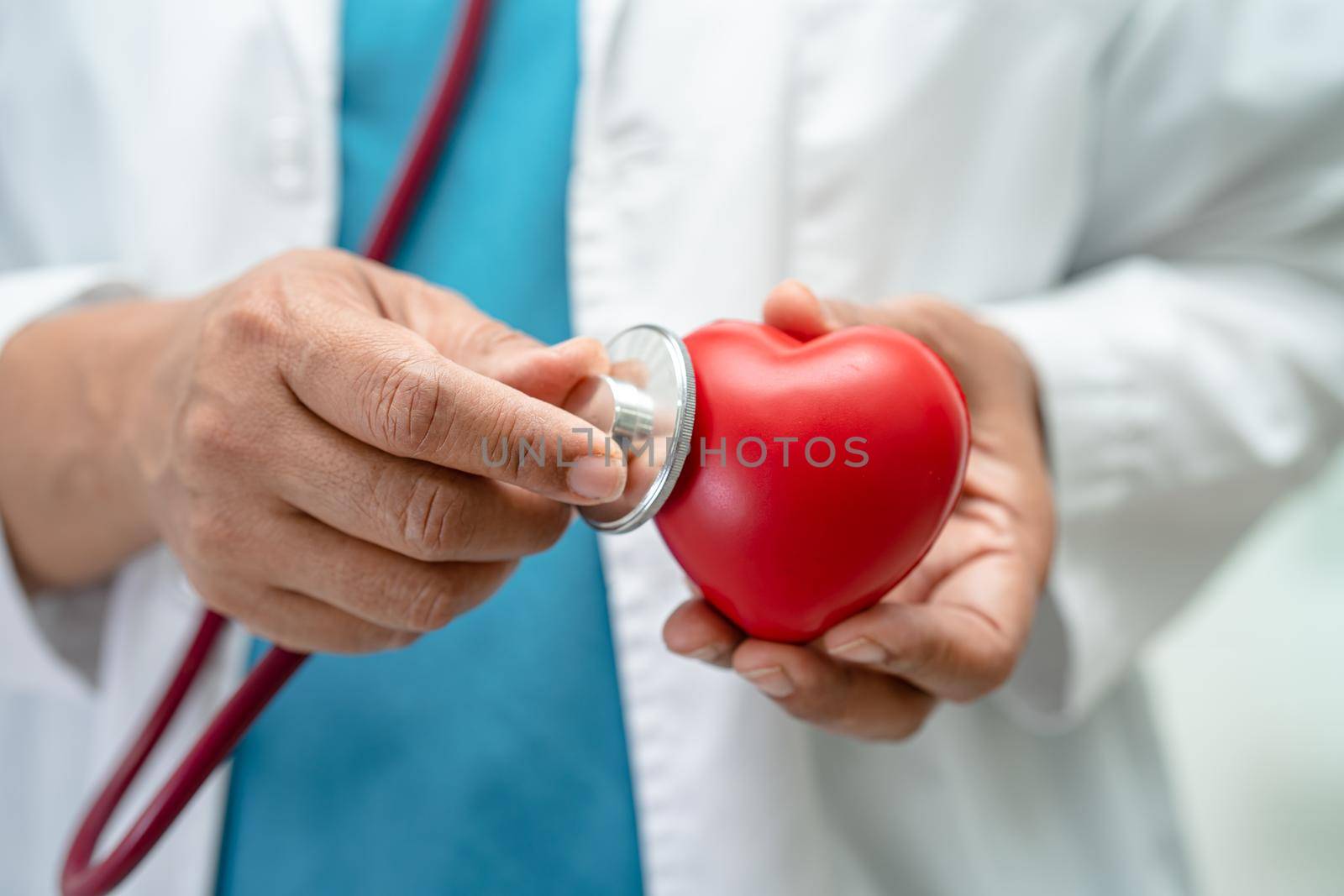 Doctor holding a red heart in hospital ward, healthy strong medical concept.