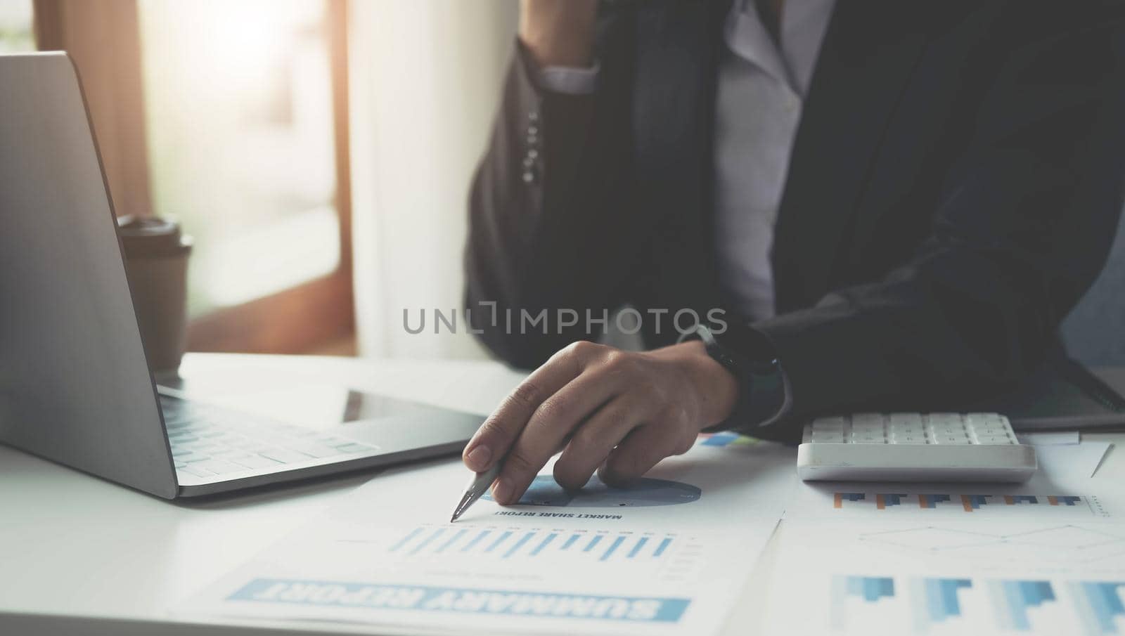 Close up Businesswoman consultant holding pen and pointing at financial on wooden desk in coffee shop. freelance, tax, accounting, statistics and analytic research concept. by wichayada