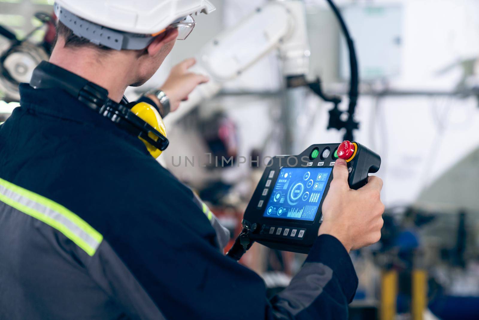 Young factory worker working with adept robotic arm in a workshop . Industry robot programming software for automated manufacturing technology .
