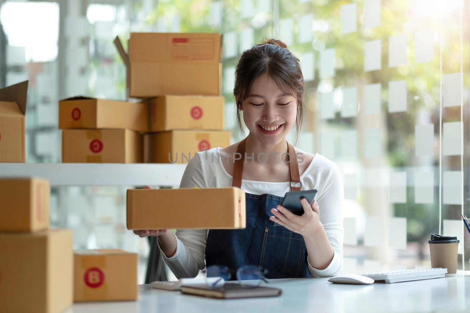 Portrait of Asian young woman working with a box at home the workplace.start-up small business owner, small business entrepreneur SME or freelance business online and delivery concept..