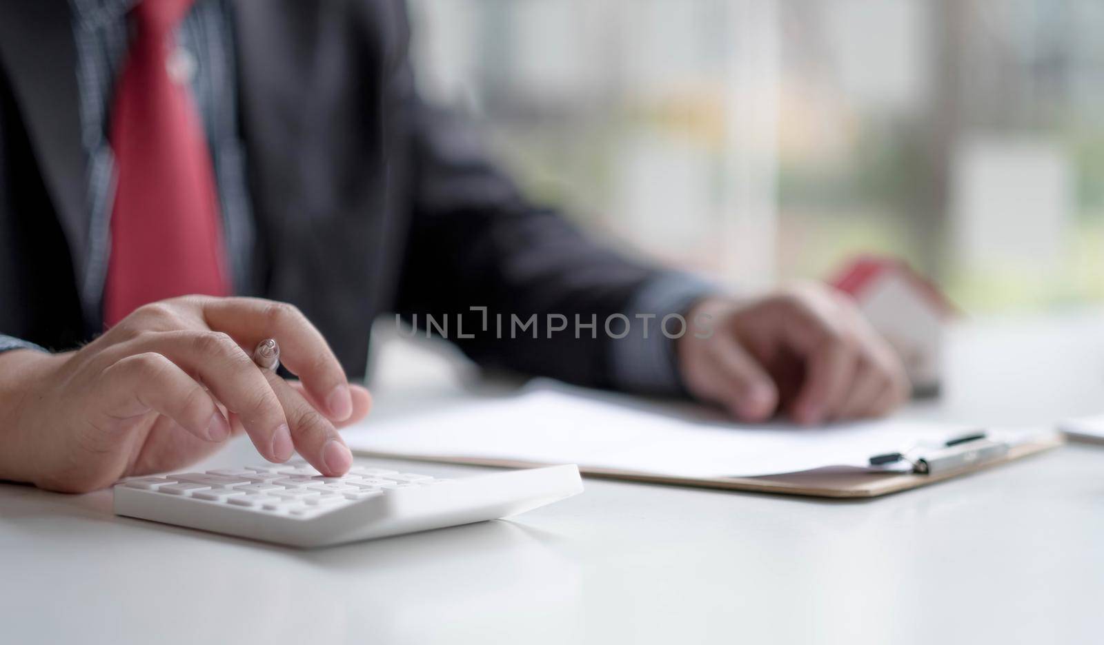 Close up Hand of Businessman calculating interest, taxes and profits to invest in real estate and home buying by wichayada
