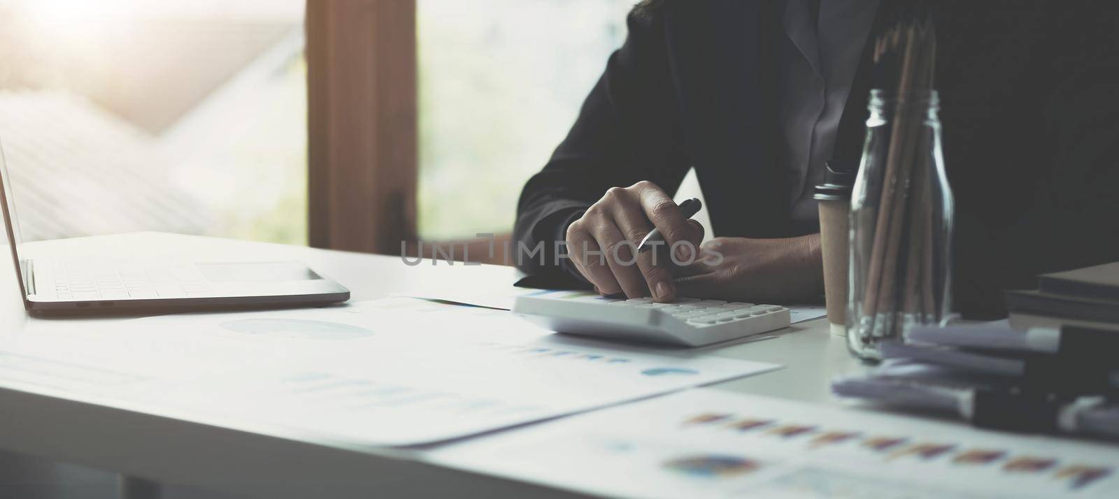 Business woman accountant or banker making calculations. Savings,Business Financing Accounting Banking and economy Concept. Image of hands using calculator on desk about cost at office..