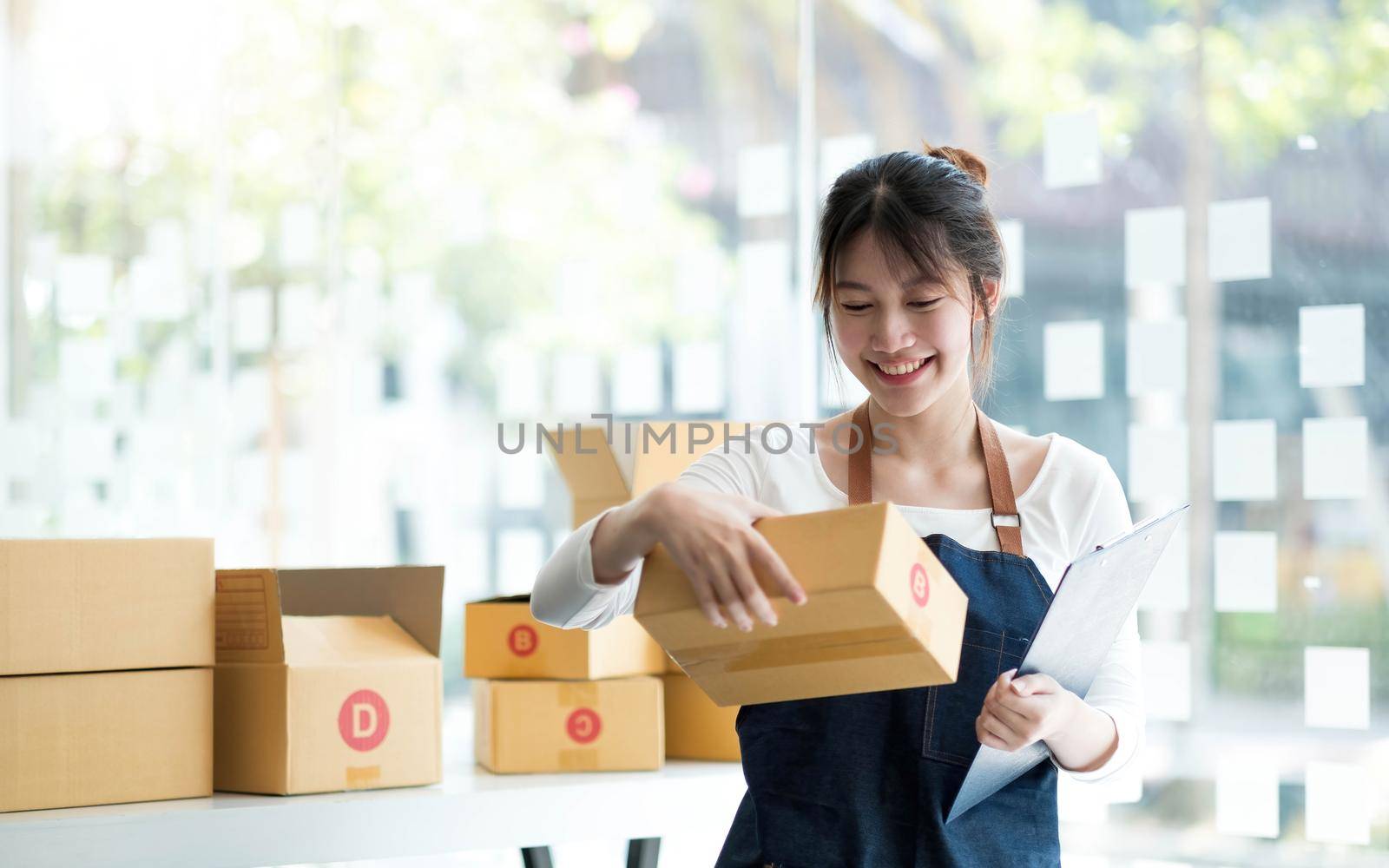 Starting small businesses SME owners female entrepreneurs Use a laptop or notebook to receive and review orders online to prepare to pack boxes, sell to customers, SME online business ideas..