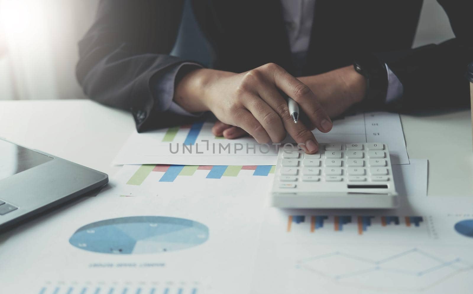 Close up Business woman using calculator and laptop for do math finance on wooden desk in office and business working background, tax, accounting, statistics and analytic research concept.