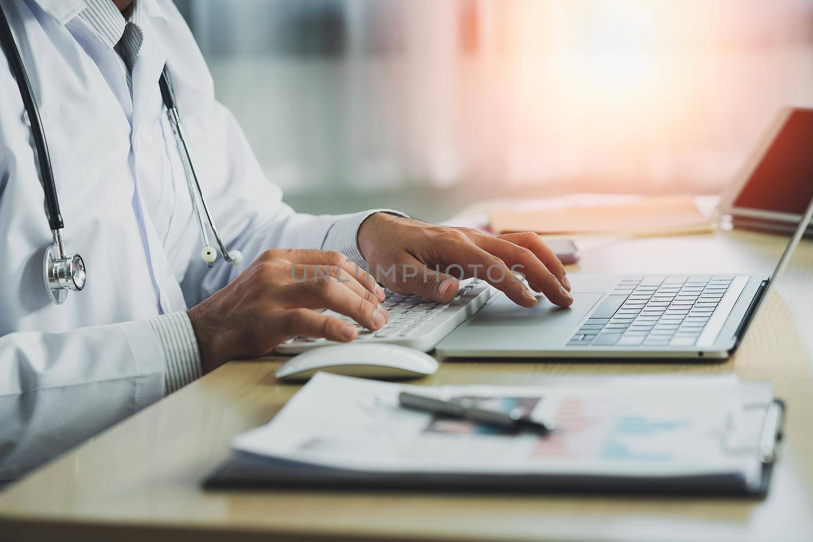 Doctor working with chart paper and laptop computer looking graph. Male doctor work at office hospital. Health hospital concept